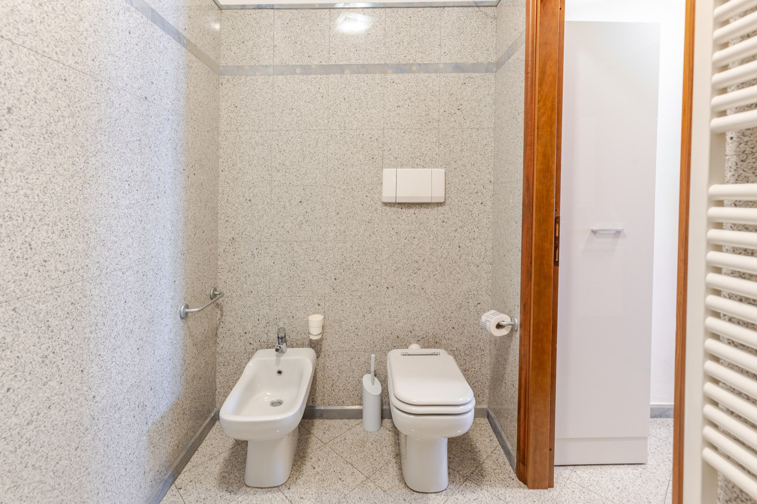A small, modern bathroom with a bidet, toilet, and a towel rack.