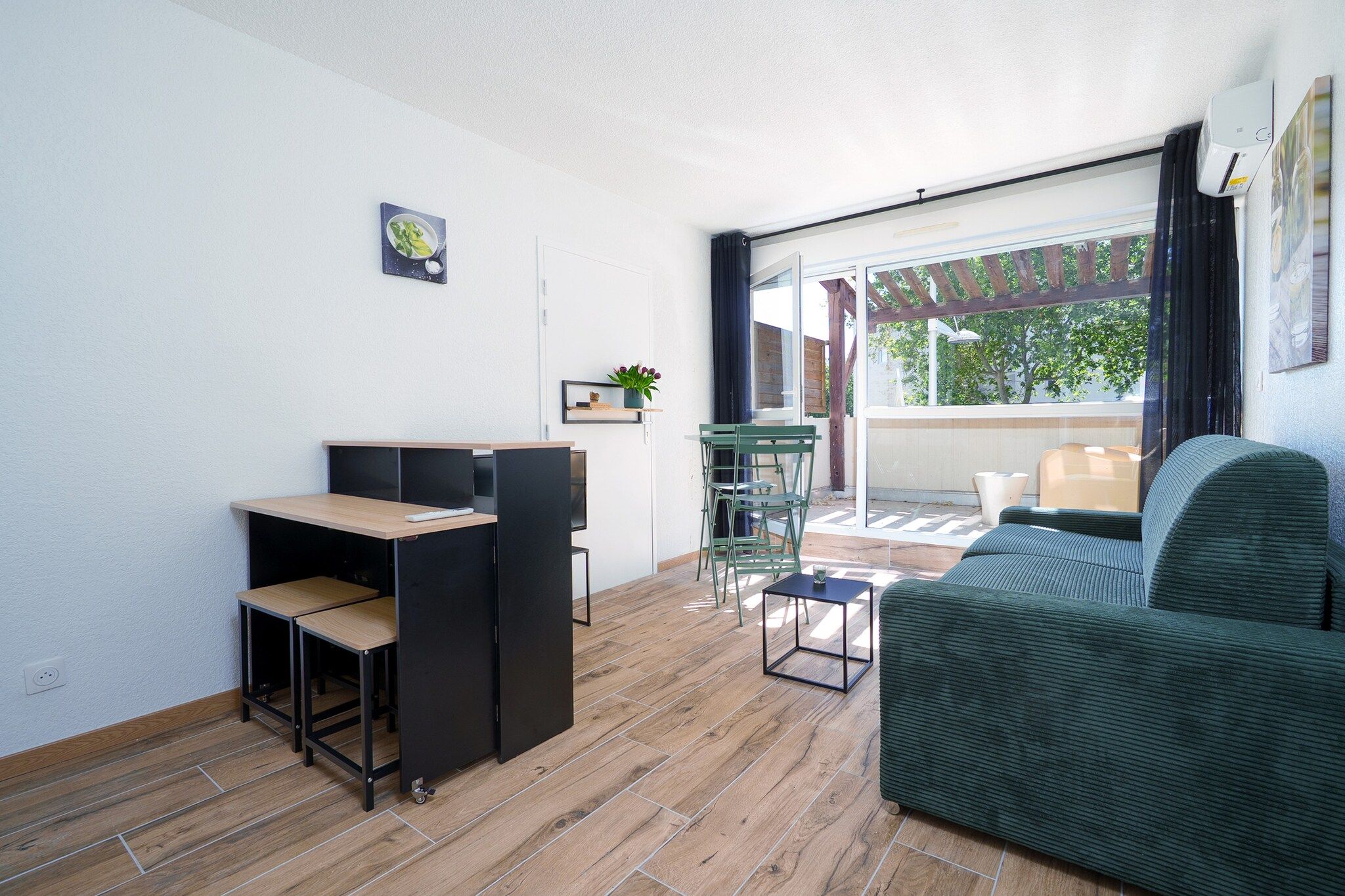 A compact living space with a sofa, a small table, a desk with a chair, and a window with curtains.