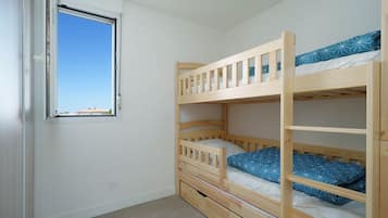 A bunk bed room with a window, a door, and a light switch on the wall.