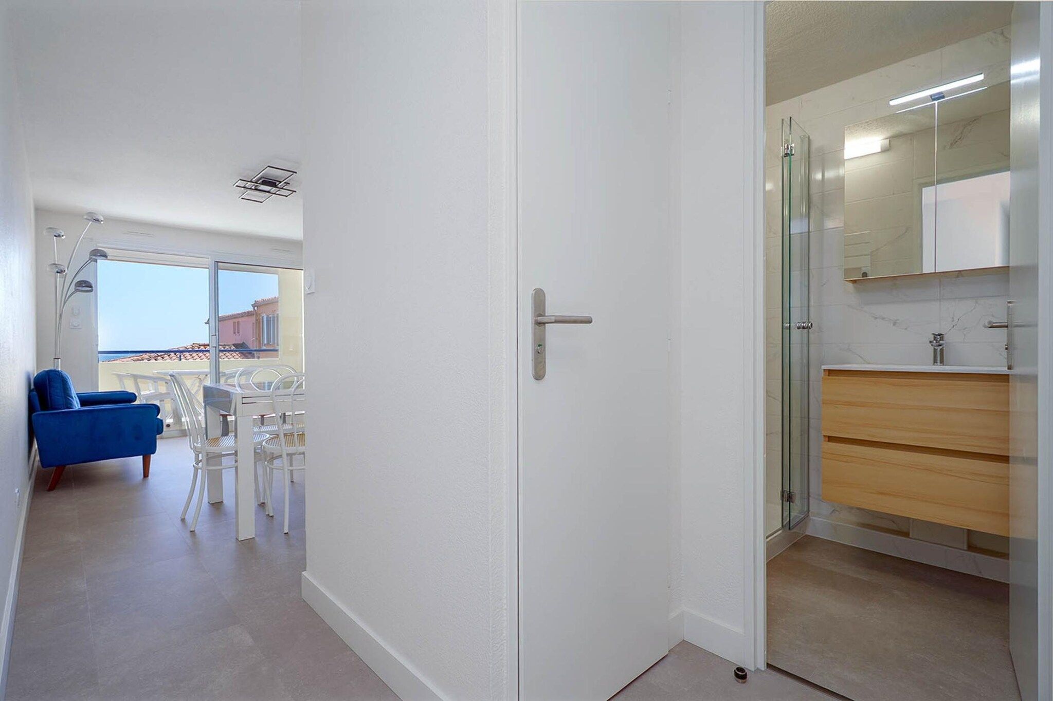 A hallway leading to a bathroom with a glass shower enclosure and a white door.