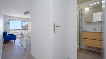A hallway leading to a bathroom with a glass shower enclosure and a white door.