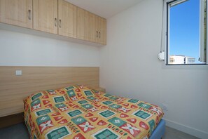 Une chambre à coucher avec un lit, une armoire en bois et une fenêtre donnant sur un beau paysage.