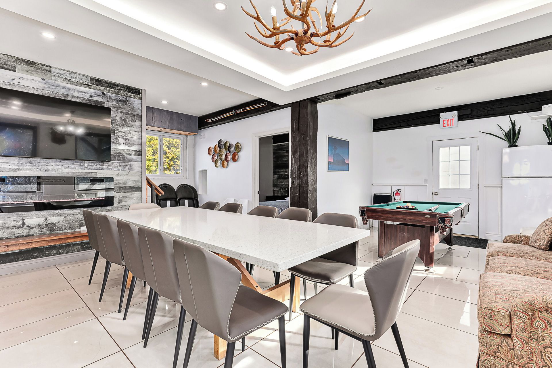 A modern kitchen with a large dining table, built-in appliances, and a pool table.
