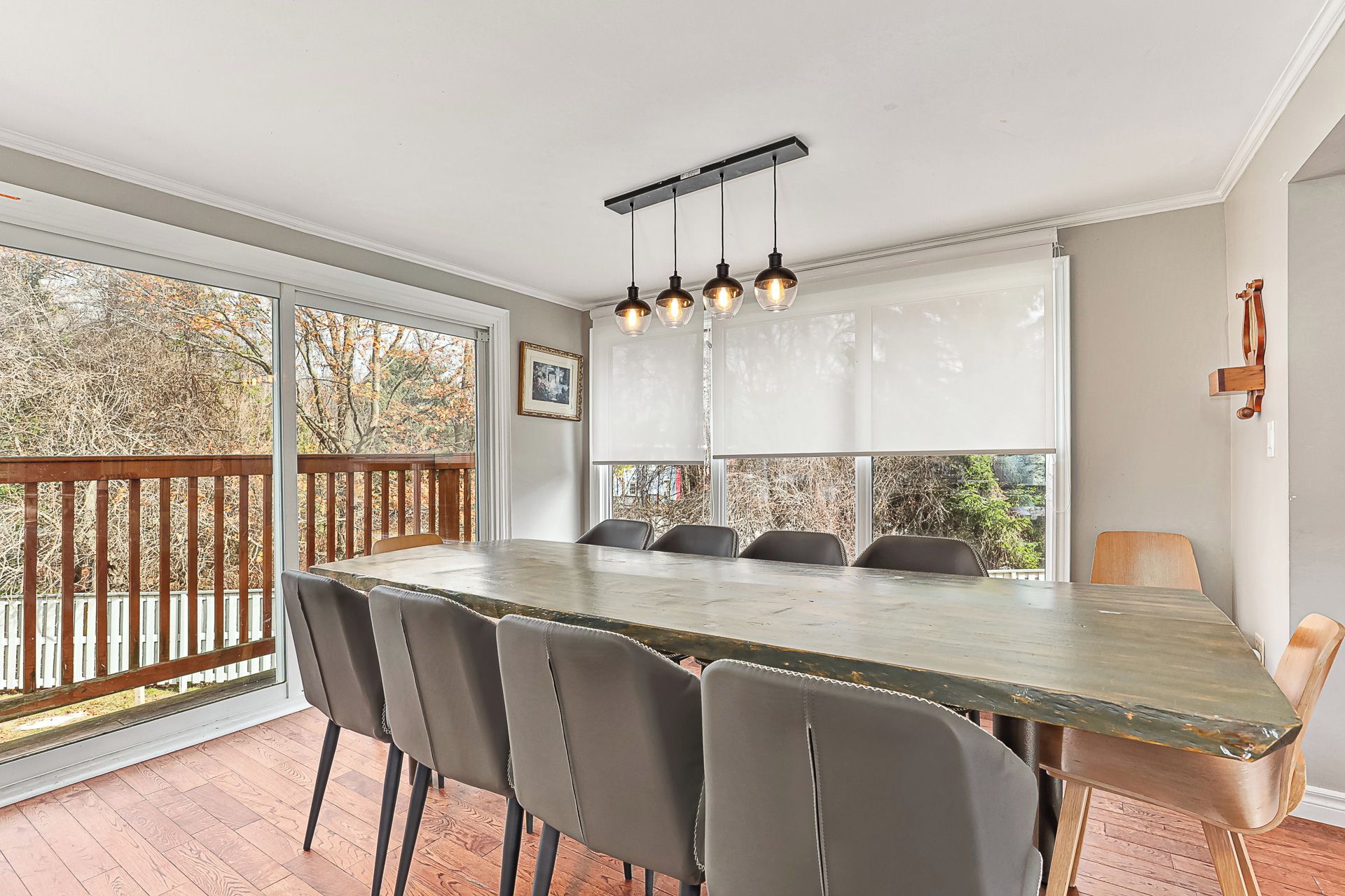 Un espace repas comprenant une longue table, six chaises et un luminaire suspendu.