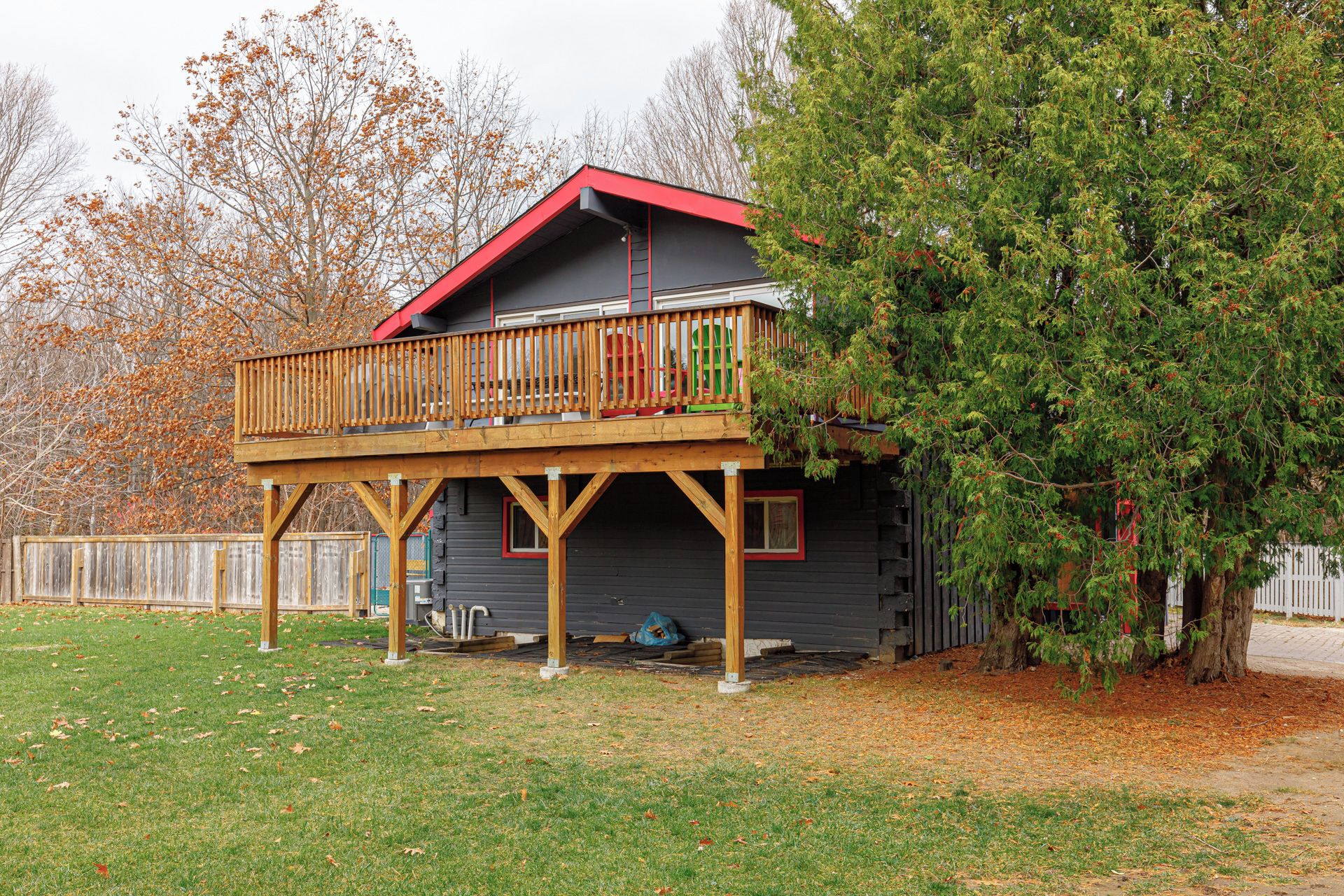 A two-story cabin with a deck and a red roof.