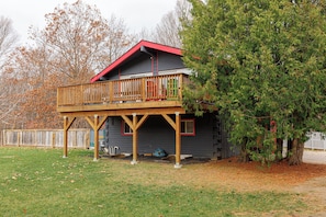 Une cabane à deux étages avec une terrasse et un toit rouge.