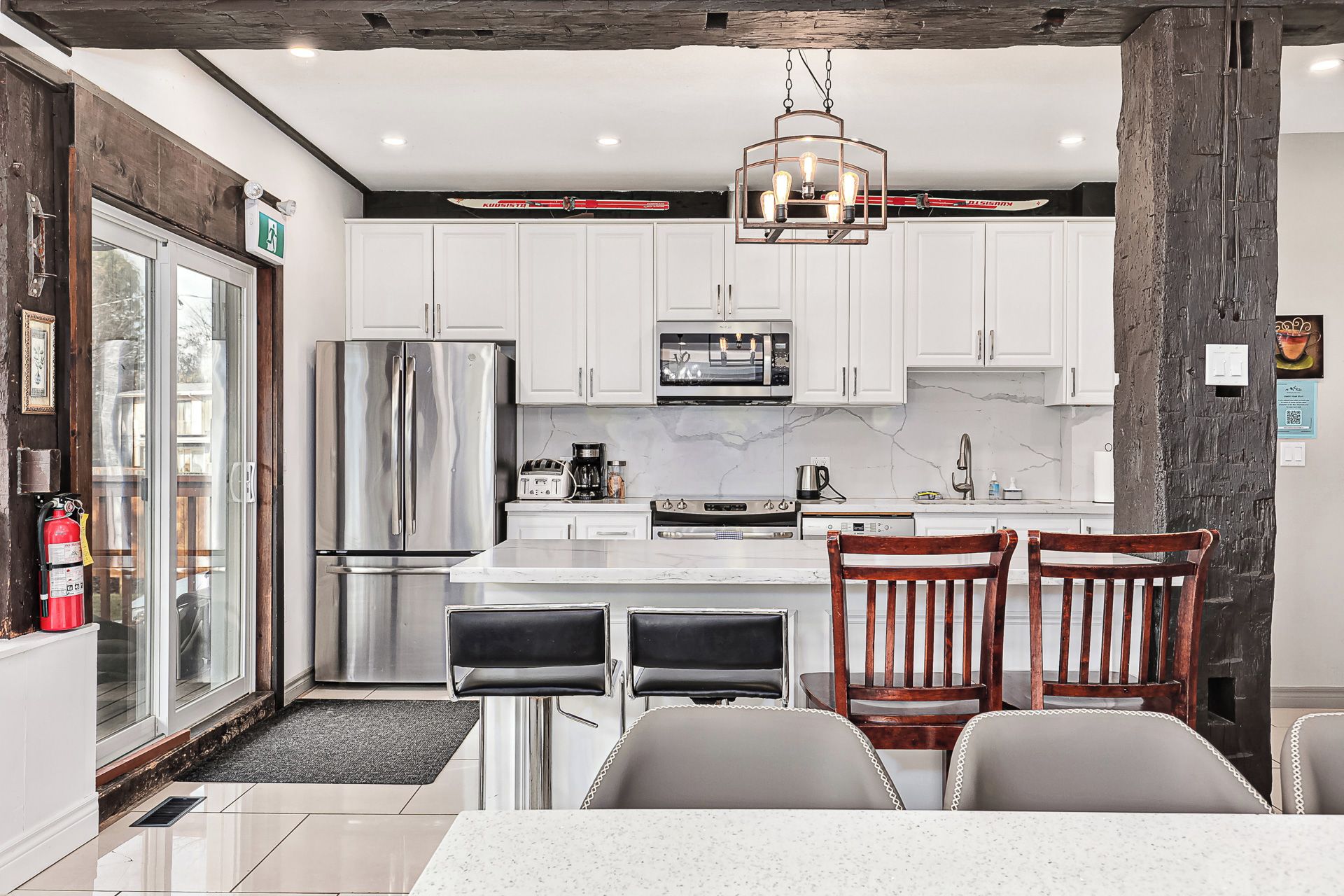 A modern kitchen with white cabinets, stainless steel appliances, and a marble countertop.