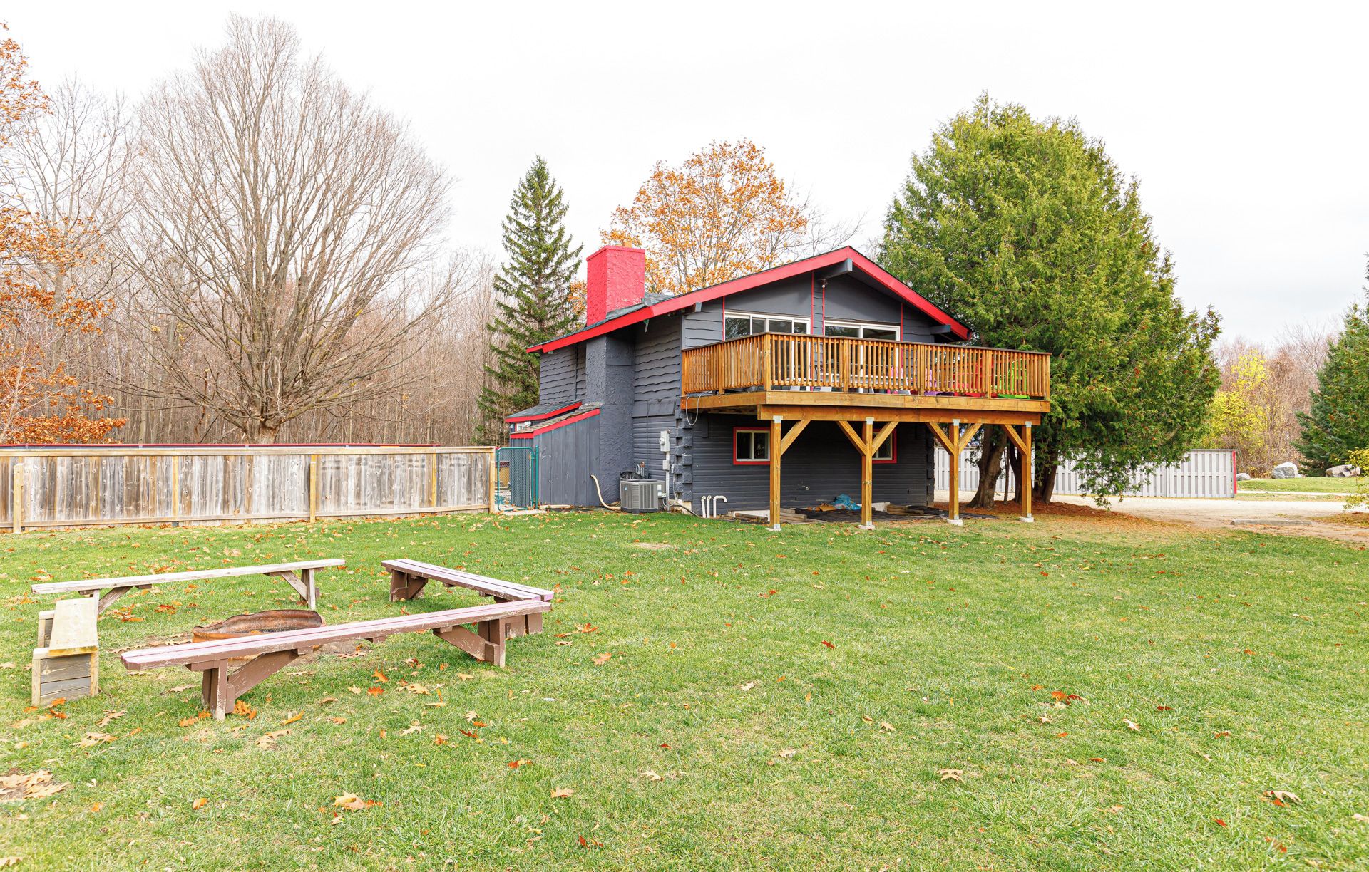 Une maison avec une terrasse en bois et une cour clôturée.