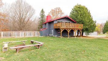 Une maison avec une terrasse en bois et une cour clôturée.