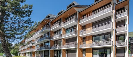 A multi-story hotel with balconies, large windows, and a wooden facade.