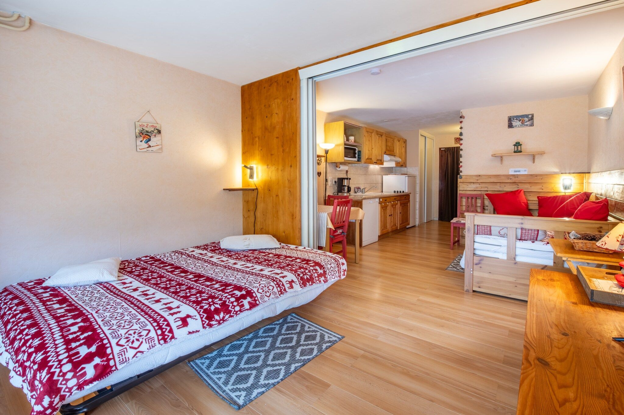 Una habitación acogedora con una cama, un escritorio de madera, una zona de cocina y una mesa de comedor.