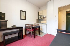 Un espace de vie compact comprenant un coin repas, une kitchenette et un téléviseur.