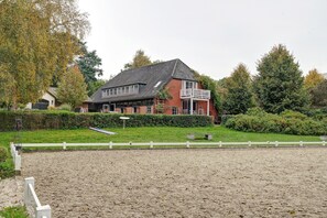 A two-story house with a balcony, surrounded by a fenced area with a gravel surface. - Idyllic, Quiet Apartment with Wi-Fi (Grebin)