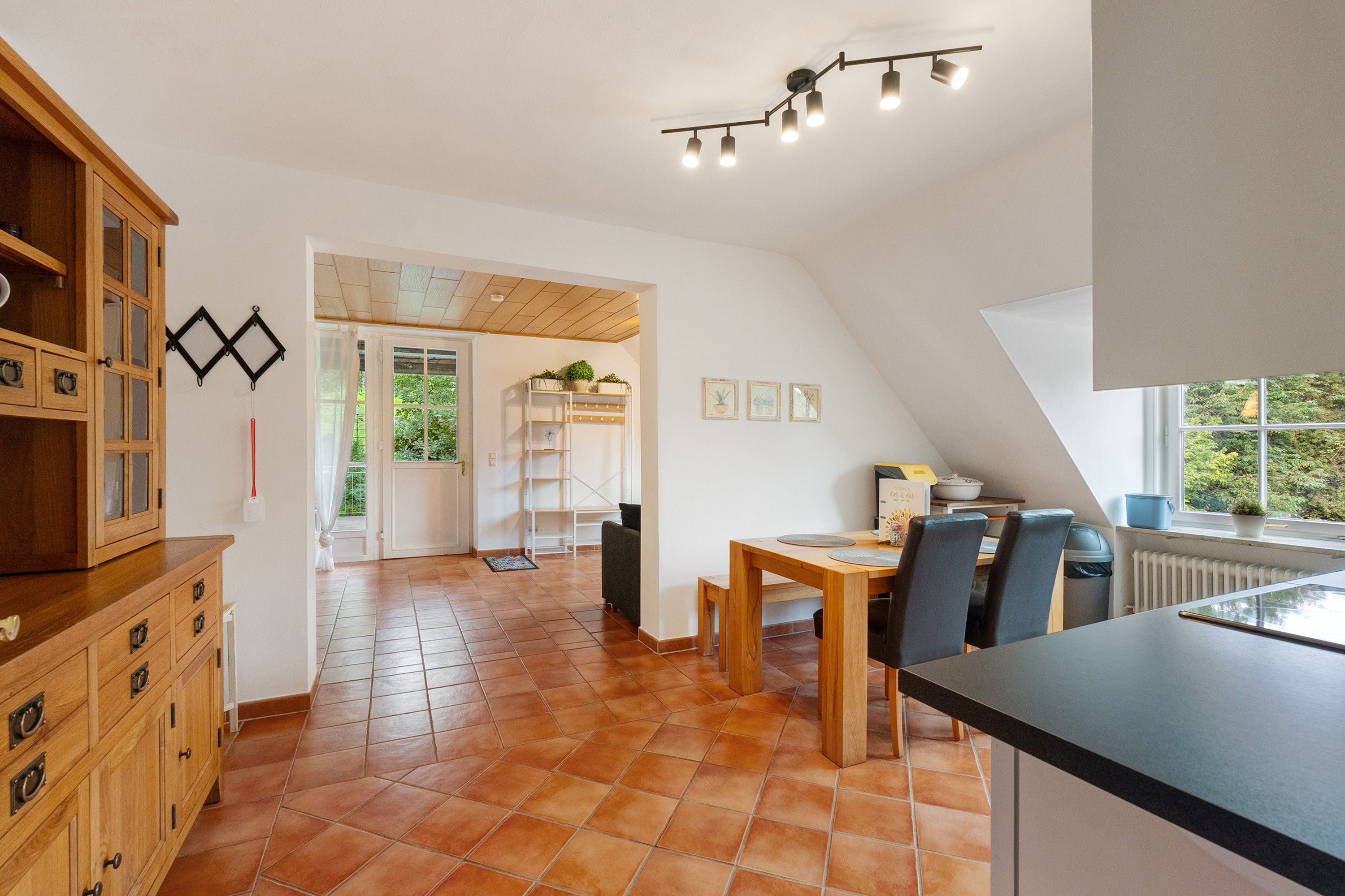 A spacious kitchen with a dining area, wooden cabinets, and a view through the door.