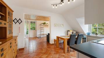 A spacious kitchen with a dining area, wooden cabinets, and a view through the door.