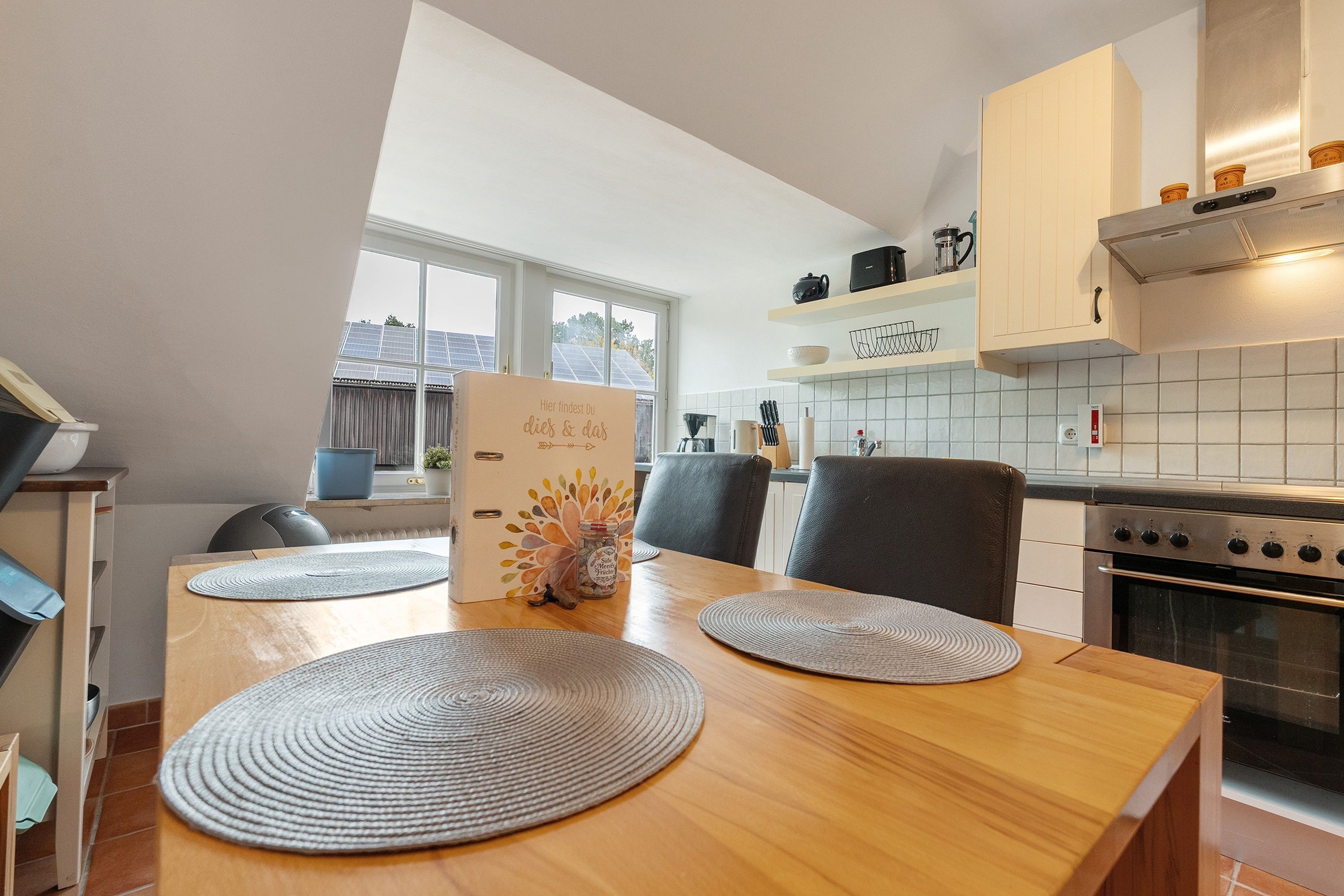 A modern kitchen with a wooden dining table, chairs, and a built-in oven.