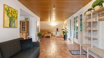 Un salon moderne avec un canapé gris, un plancher en bois et un plafond avec des poutres apparentes.
