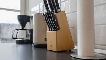Una encimera de cocina con una cafetera, un bloque de cuchillos y un rollo de papel de cocina.