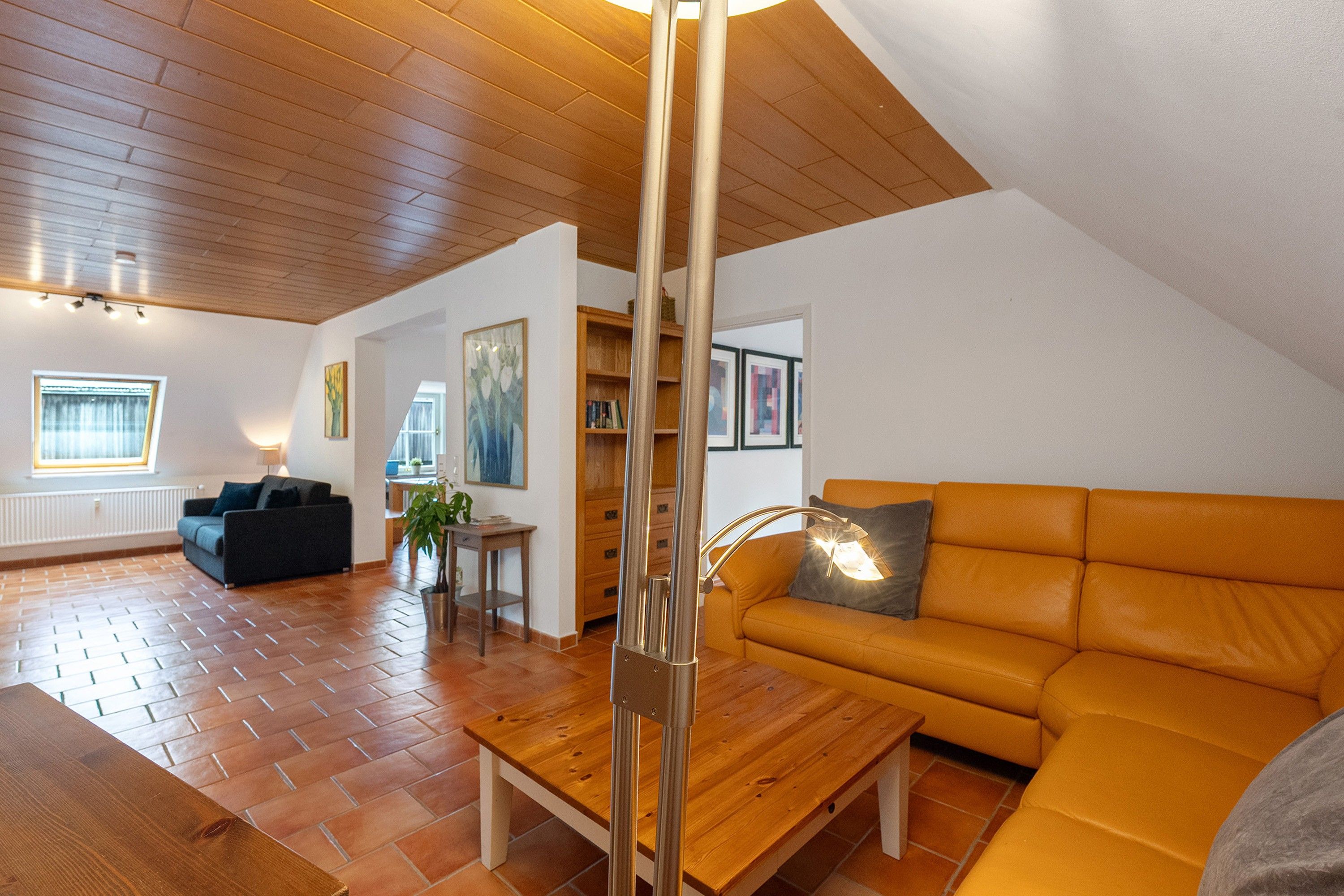 Een moderne woonkamer met een houten plafond, een bank, een salontafel en een eethoek met een tafel en stoelen.