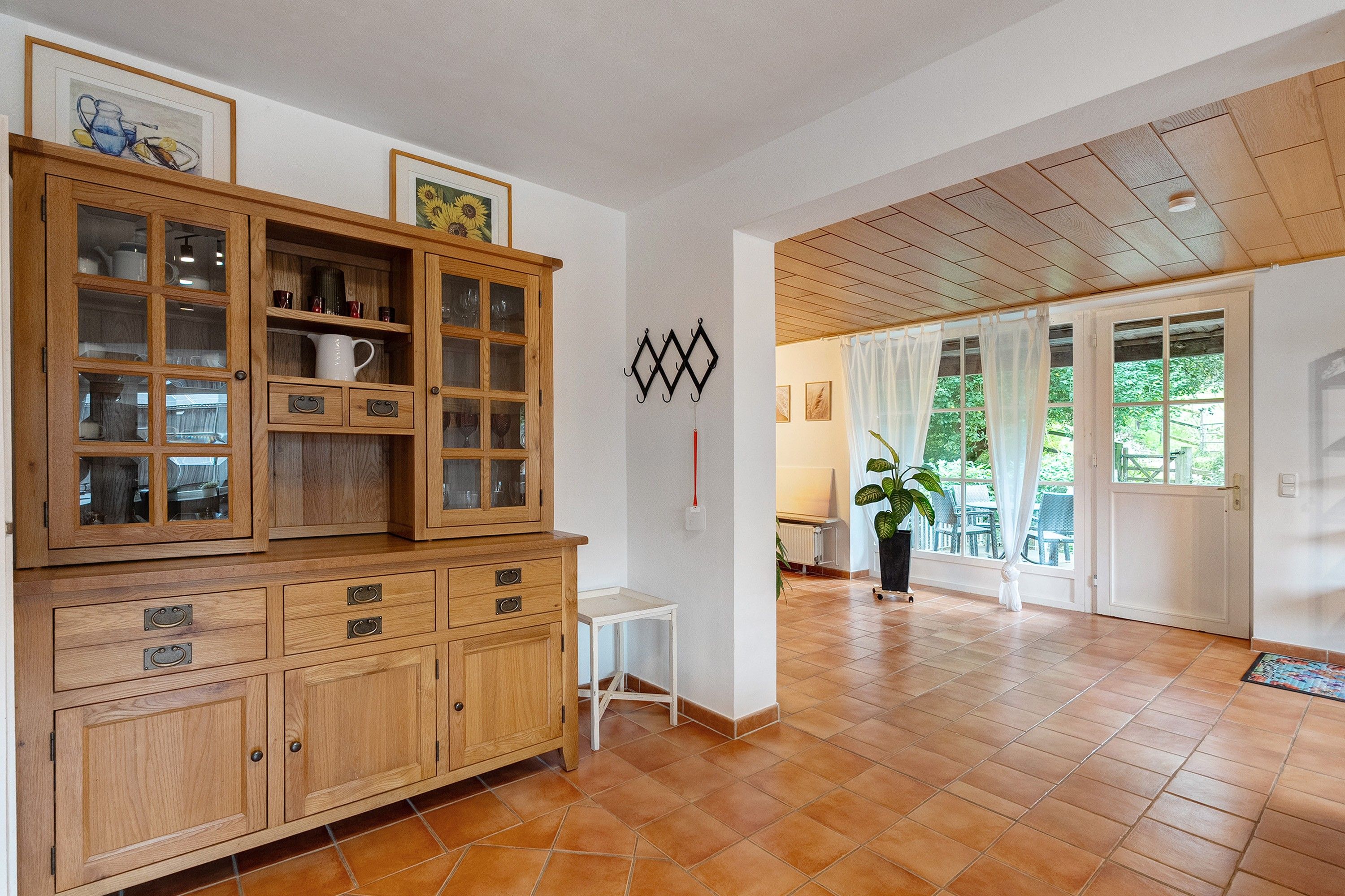 A spacious room with a wooden cabinet, a white chair, and a potted plant.