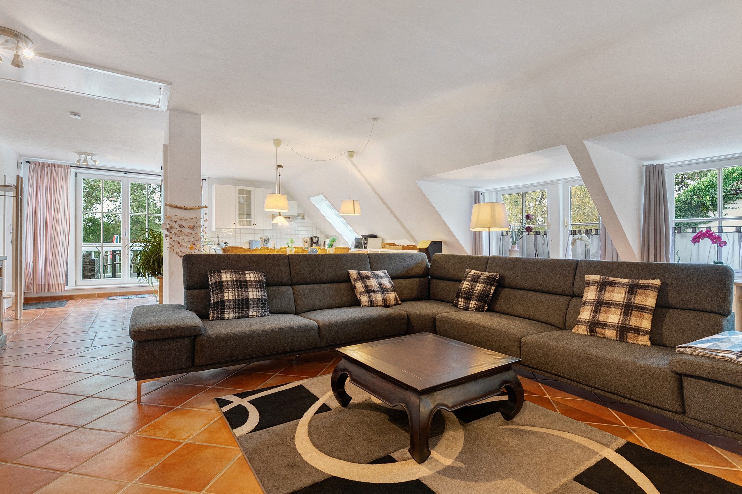 A spacious living area with a sectional sofa, a coffee table, and a kitchen in the background.
