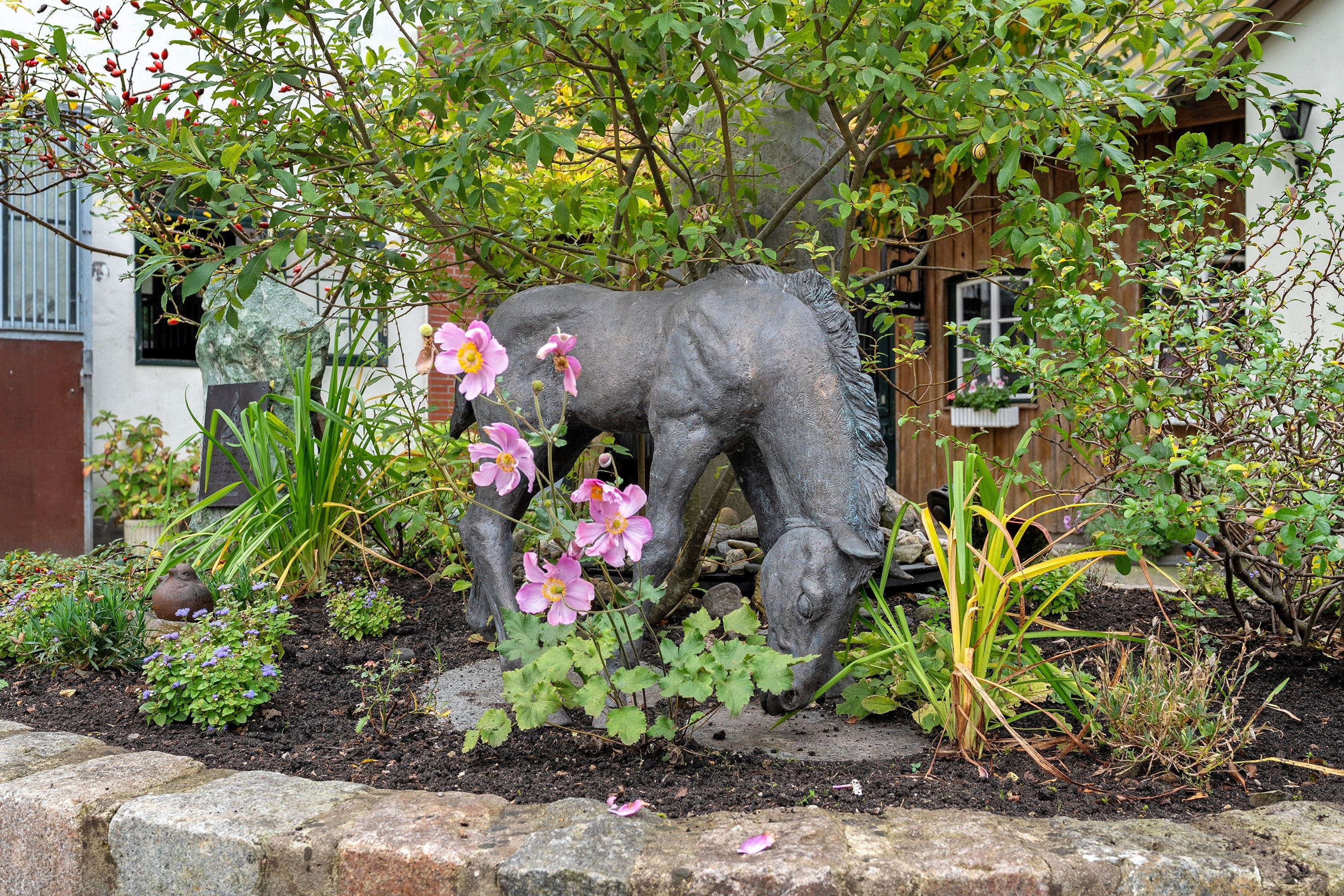 A garden with a stone elephant sculpture surrounded by flowering plants and greenery.