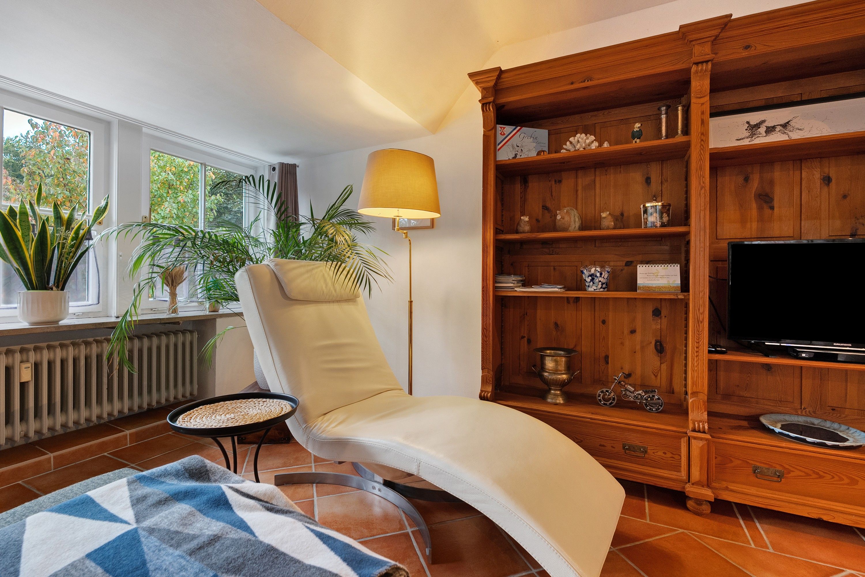 A living room with a sofa, a wooden bookshelf, a television, and a floor lamp.