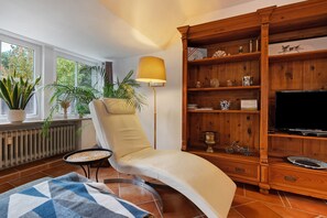 A living room with a sofa, a wooden bookshelf, a television, and a floor lamp.