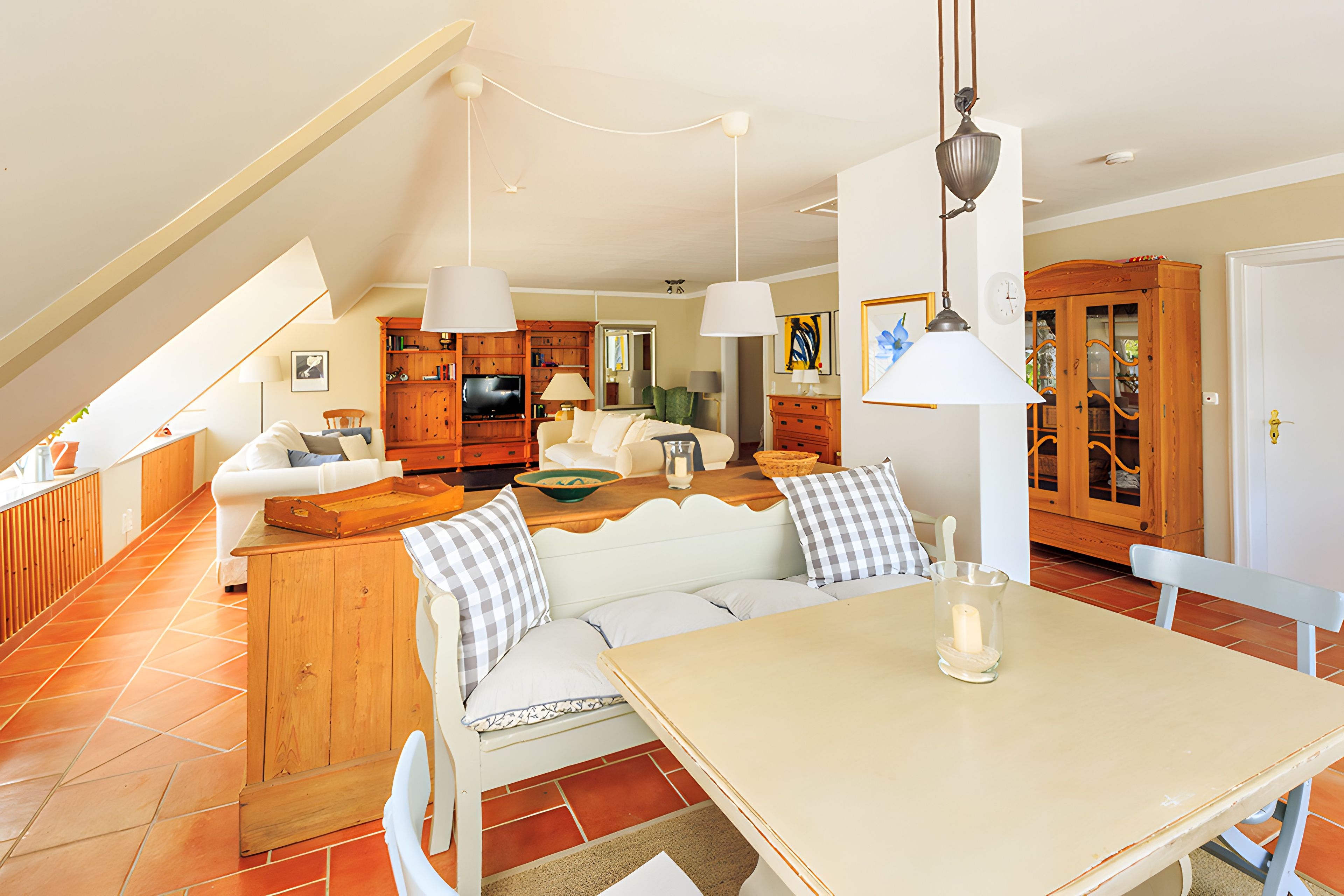 A spacious living area with a high ceiling, a dining table, and a kitchen in the background.