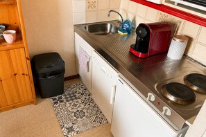 Eine kleine Küche mit Spüle, Kaffeemaschine, Toaster und Geschirrspüler.