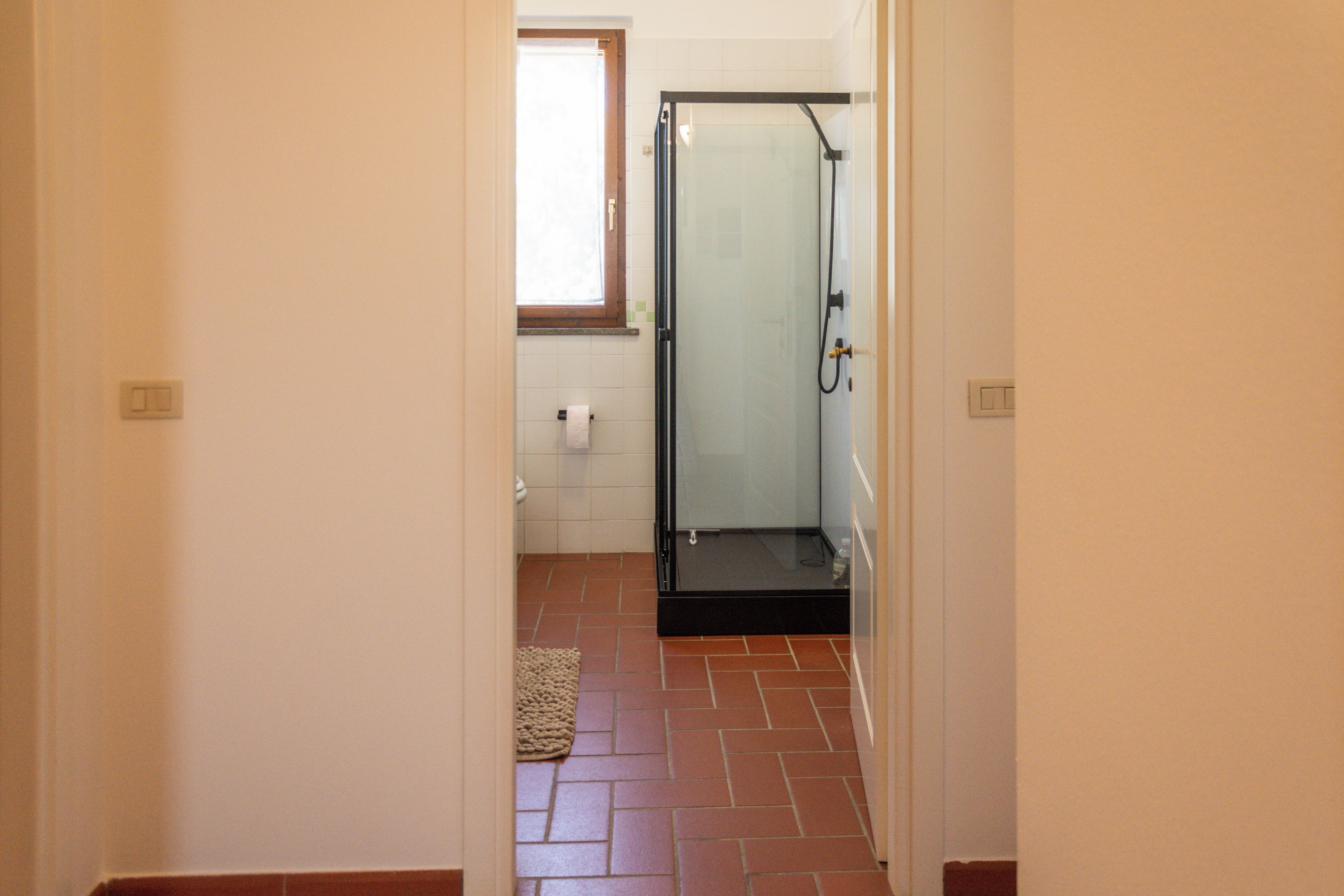 A bathroom with a shower, a toilet, and a towel rack.