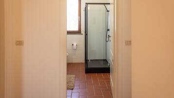 A bathroom with a shower, a toilet, and a towel rack.