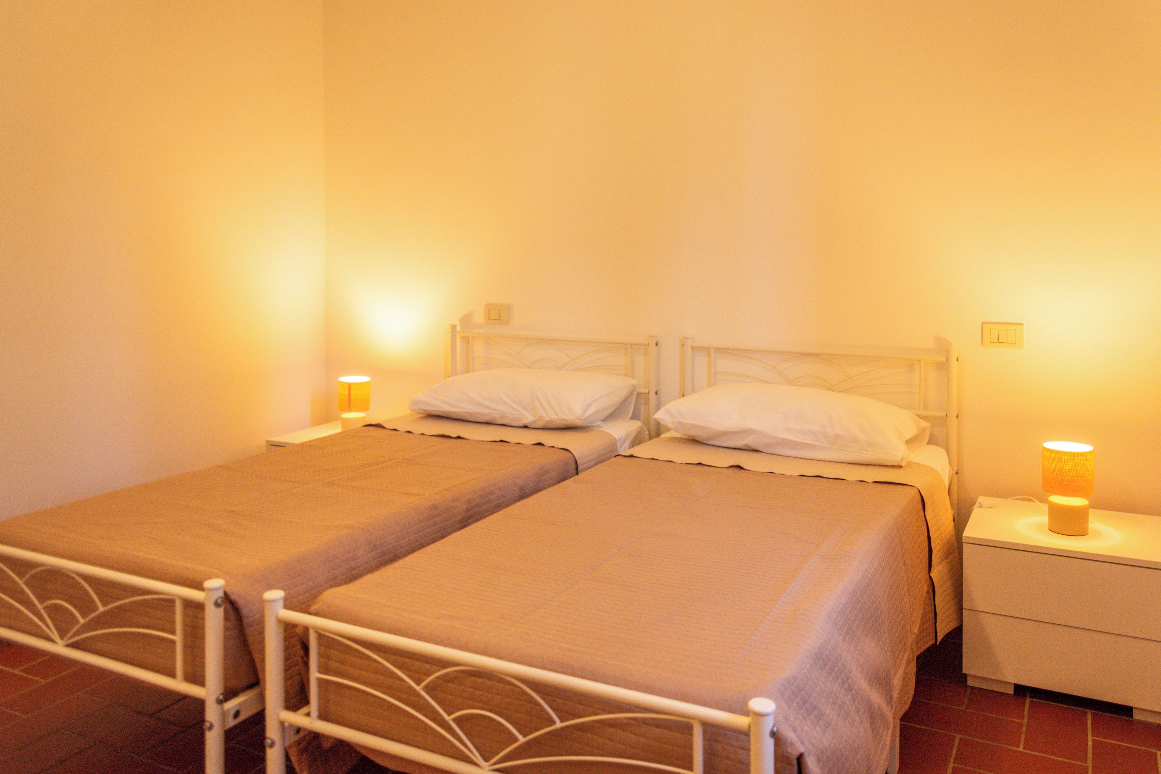 A double bed with a metal frame, two bedside tables, and two wall-mounted lamps.