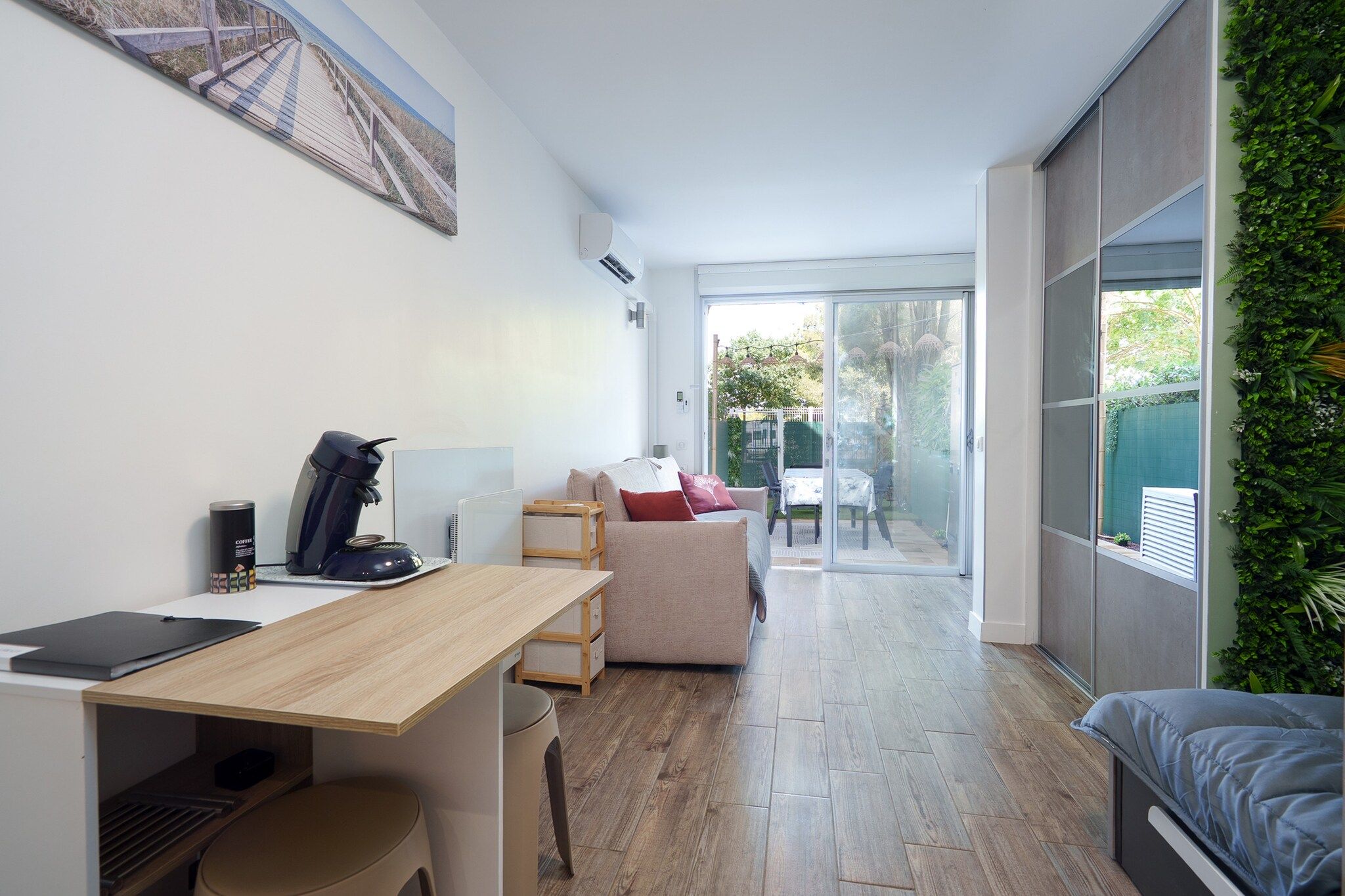 A modern, compact living space with a wooden desk, a sofa, and a bed.