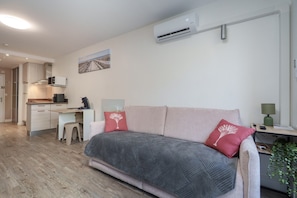 Ein modernes Schlafzimmer mit einer Couch, einem Schreibtisch und einer Klimaanlage.