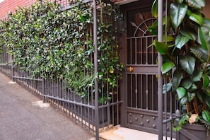 A gated property with a metal fence and a door, surrounded by lush greenery. - Regal House Roma Capucci (Rome)