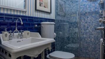 A bathroom with a white sink, a toilet, and a shower area with blue mosaic tiles.