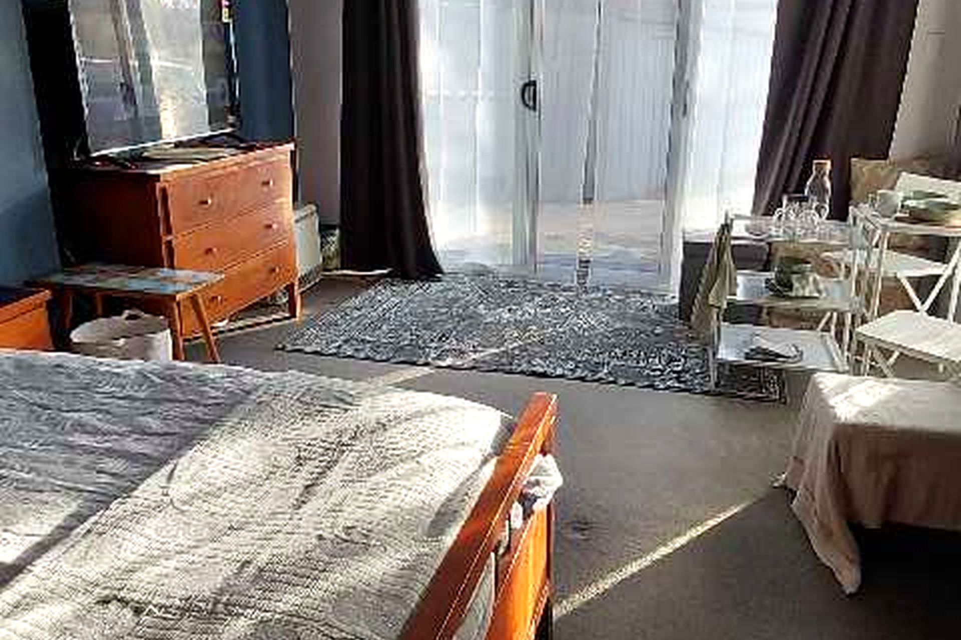A bedroom with a bed, dresser, and a desk with a chair.