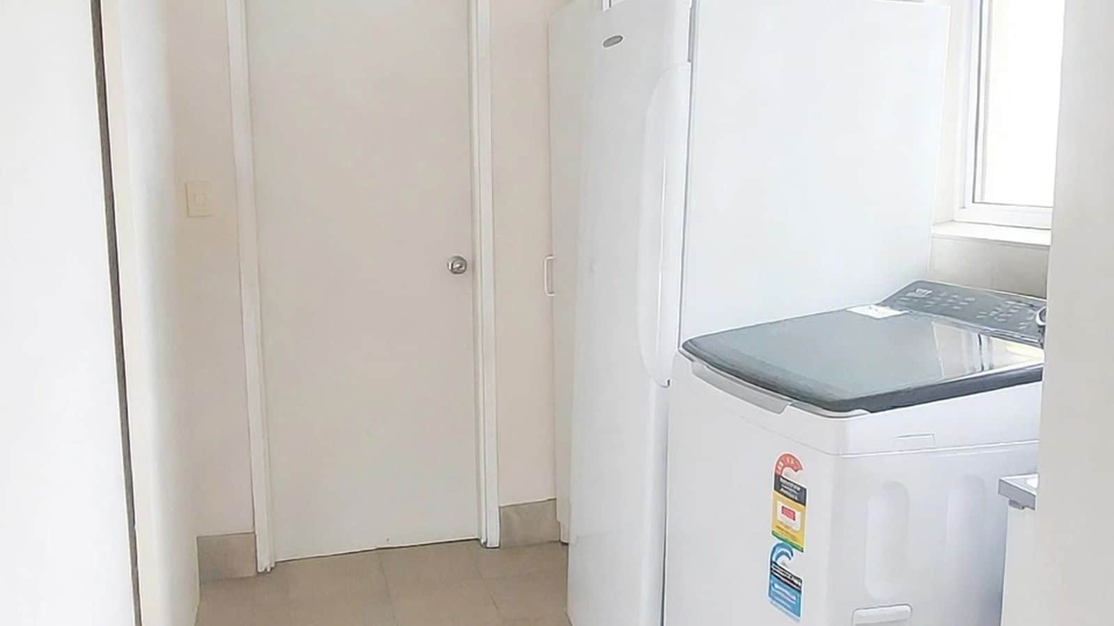A compact kitchen with a white refrigerator, a door, and a window.