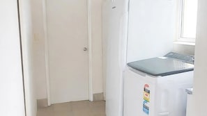 A compact kitchen with a white refrigerator, a door, and a window.