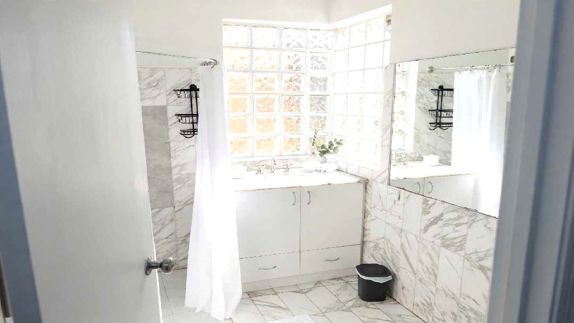 A bathroom with a shower, a sink, and a mirror.