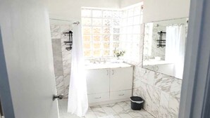 A bathroom with a shower, a sink, and a mirror. - Cozy 1-bedroom apartment in welcoming Cottesloe with AC (Cottesloe)