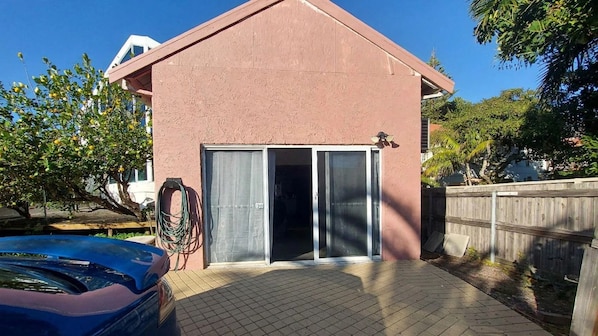A residential building with a garage door, a hose, and a blue car parked in front.