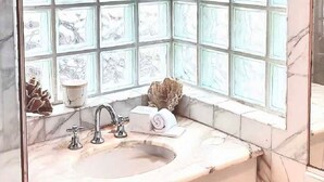 A bathroom with a marble sink, a window with decorative panels, and a towel on the counter. - Cozy 1-bedroom apartment in welcoming Cottesloe with AC (Cottesloe)