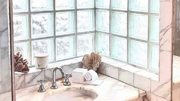 A bathroom with a marble sink, a window with decorative panels, and a towel on the counter.