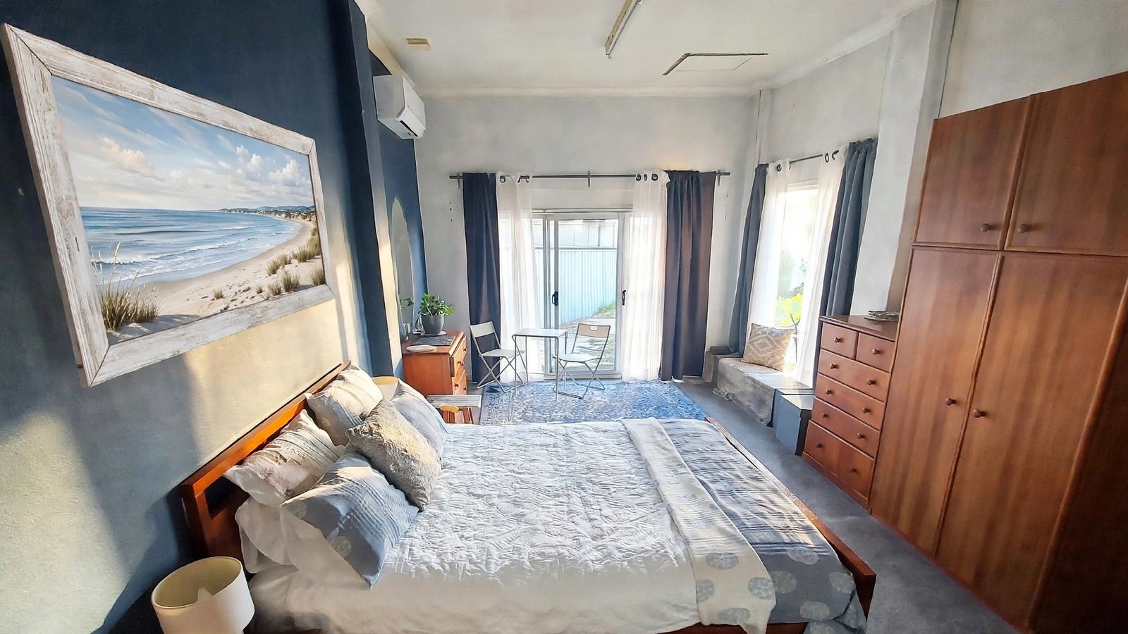 A bedroom with a bed, a wardrobe, a desk, and a chair.