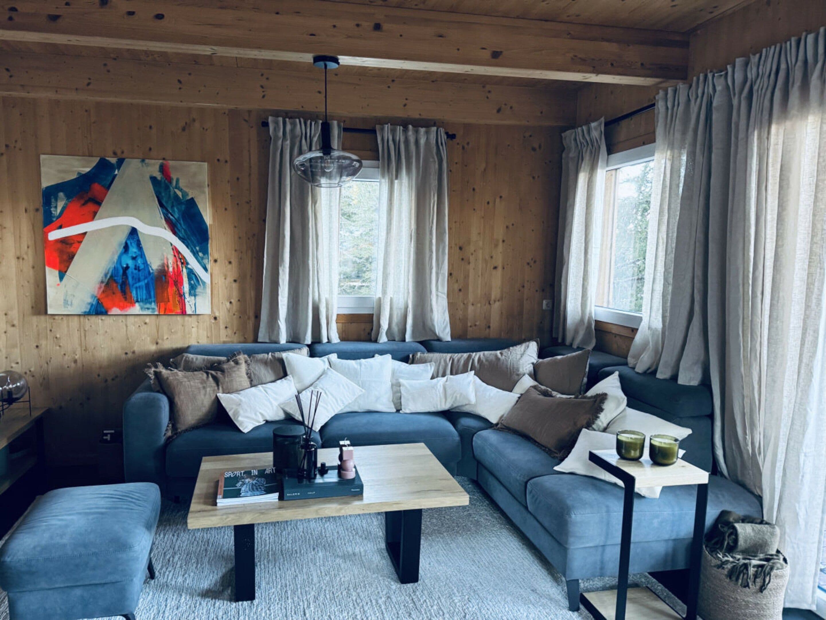 A cozy living room with a sectional sofa, a coffee table, and a painting on the wall.
