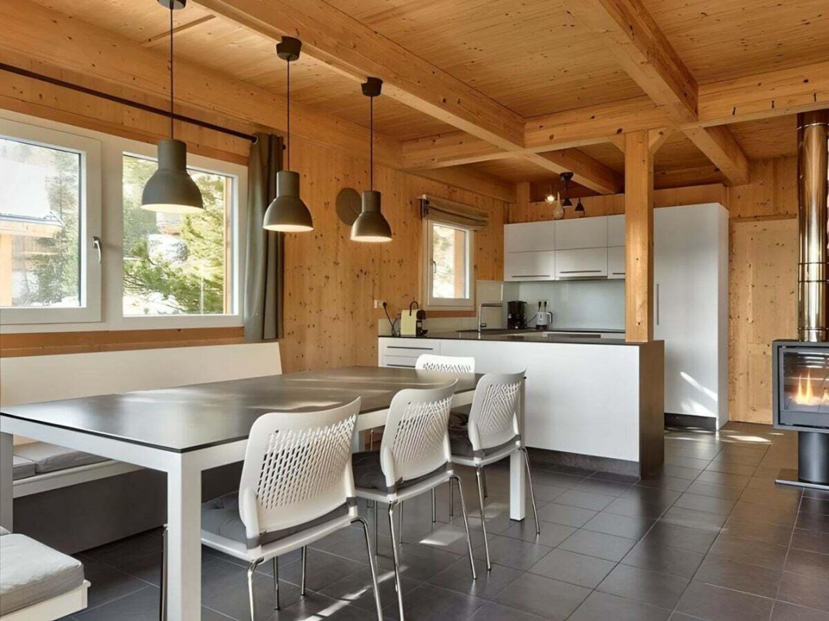 A modern kitchen with a central island, pendant lighting, and a wood-paneled ceiling.