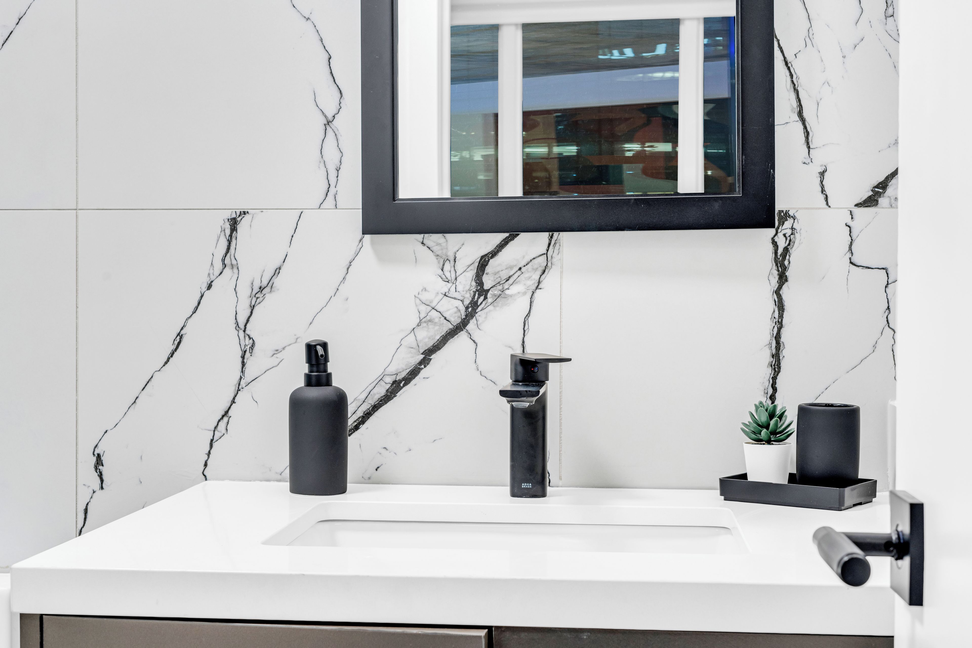 A bathroom with a white marble sink, a black faucet, and a mirror above it.