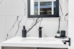 A bathroom with a white marble sink, a black faucet, and a mirror above it.
